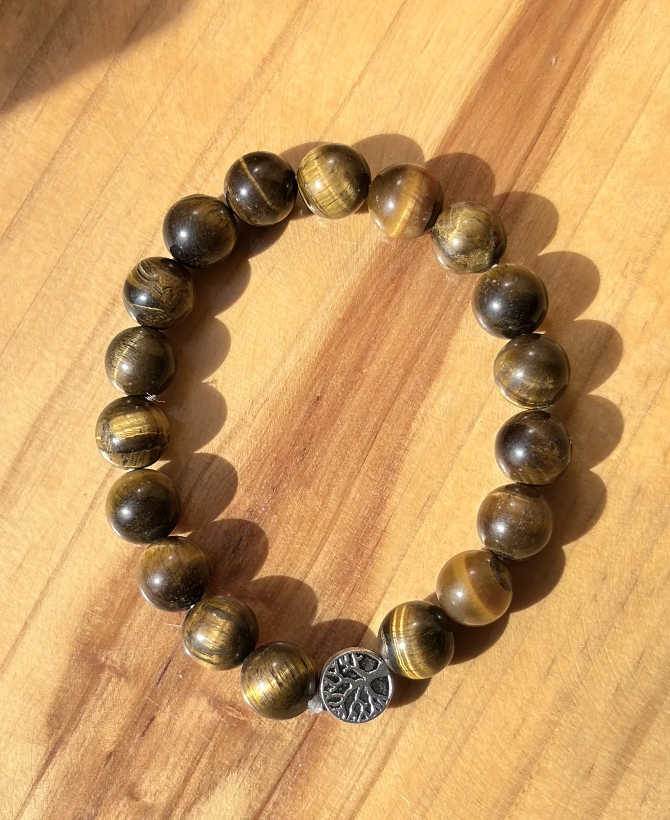 Tiger eye bracelet with a tree of life charm on wood